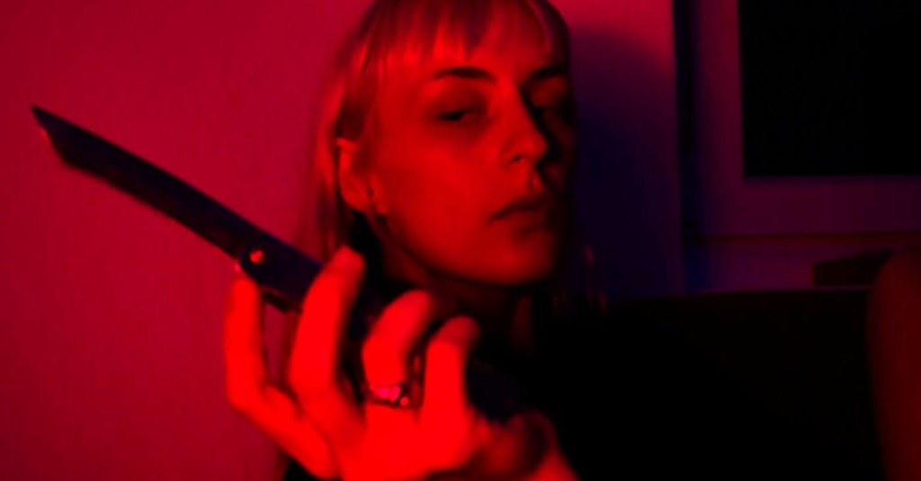 A red colored picture of a blonde-haired woman holding a knife in her one hand