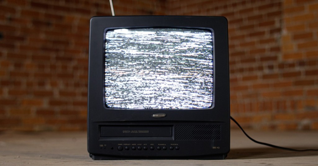 An old model black colored TV with static across its screen
