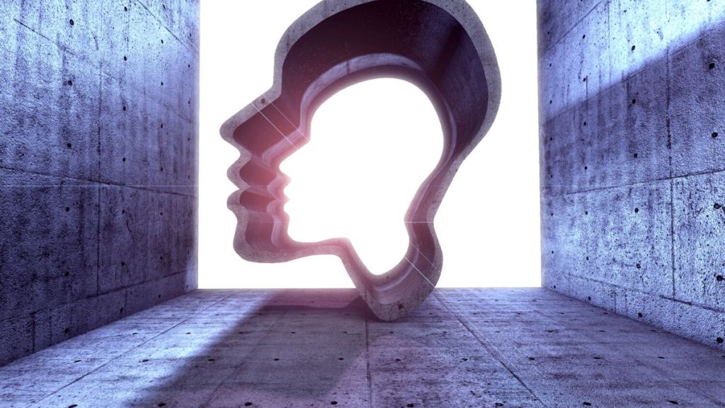 The empty glowing silhouettes of two side posed faces, one white, the other black and stone floors and walls around them