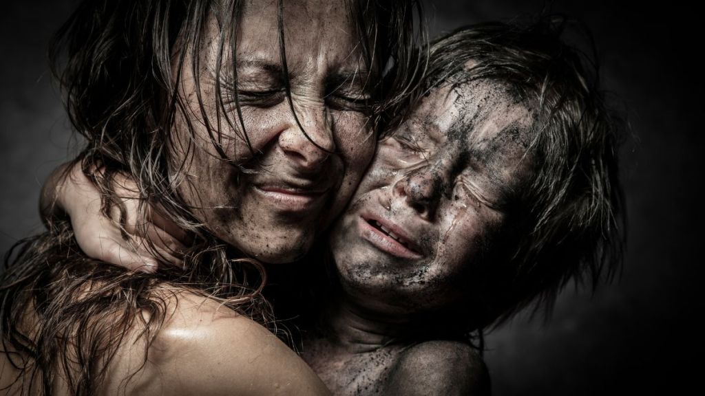 A close up of a mother and child, dirty and poor, crying and hugging each other