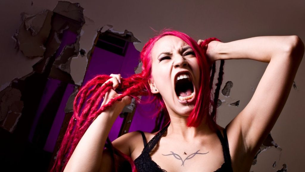 A woman with hot pink dreadlocks screaming and pulling her hair in frustration